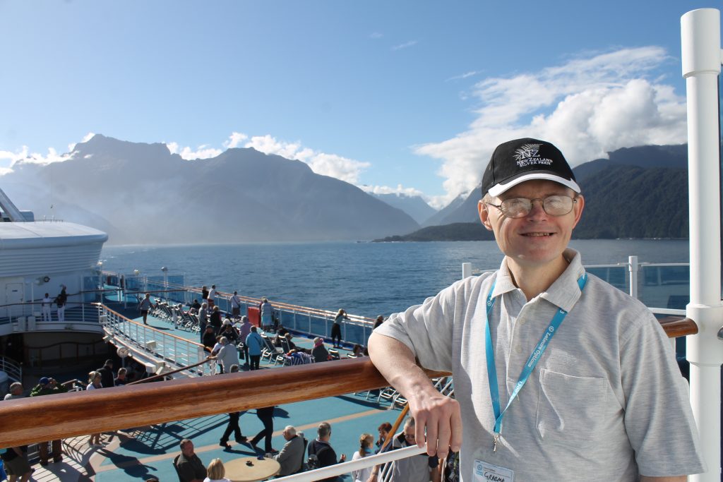 Man with a cap posing on a cruise ship in New Zealand