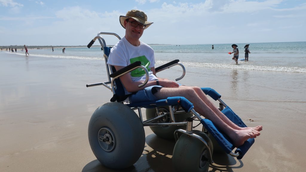 Man in wheelchair on the beach while on supported holiday with Leisure Options