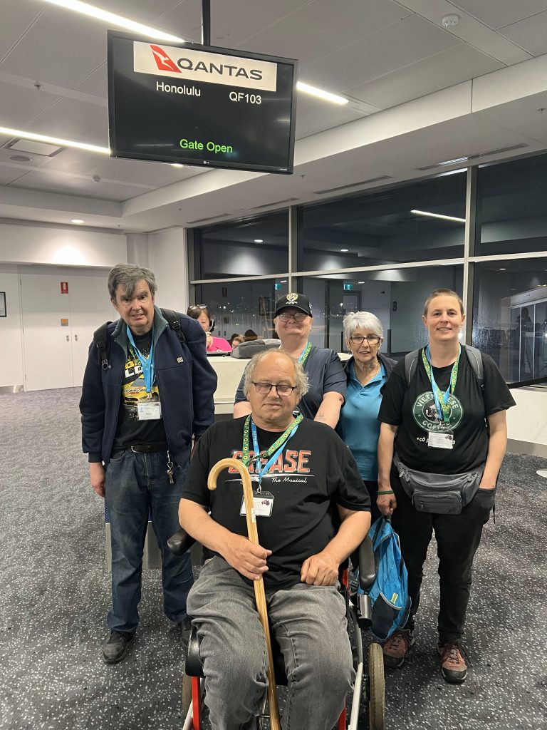 A group of travellers with a disability, wearing sunflower lanyards, getting ready to get onboard a flight at the airport.